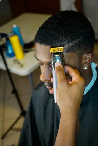 Man in a barber chair receiving a long-needed lineup from a professional barber
