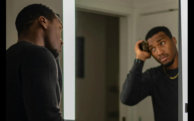 Young man brushing his hair in a bathroom mirror